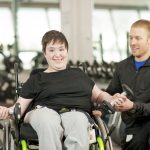Disabled female in wheelchair exercising with trainer.