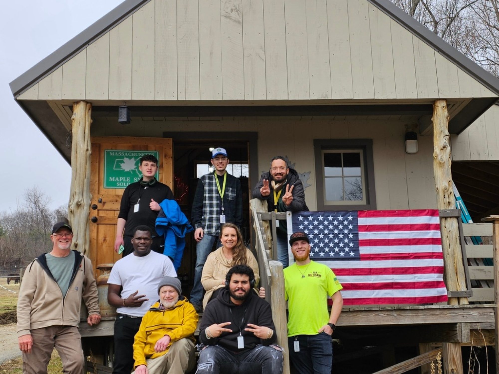 Venture Community Services staff and program participants posing outside a rustic program building